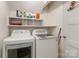 Bright laundry room features white appliances and a shelf for storage at 6921 Thermal Rd, Charlotte, NC 28211