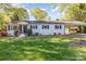 Charming, one-story home with white brick, dark shutters, covered carport and a lush, green lawn at 706 Lowell Ave, Lowell, NC 28098
