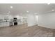 Bright, open-concept living room with new laminate flooring and a view of the modern kitchen at 908 Woodside Dr, Kings Mountain, NC 28086