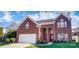 Charming two-story red brick home with a well-manicured lawn and attached two car garage at 98 Poplar Woods Dr, Concord, NC 28027
