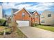 Two-story red brick home with a two-car garage and well-kept lawn with partial driveway view at 98 Poplar Woods Dr, Concord, NC 28027