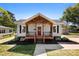 Charming home with a covered front porch, red door, gray siding, and manicured landscaping at 103 Park Ave, Mount Holly, NC 28120