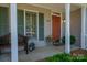 Inviting front porch with decorative features, a cozy bench, and an orange front door at 107 Southfork Dr, Belmont, NC 28012