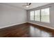 Spacious bedroom featuring hardwood floors, ceiling fan, and bright natural light from large window at 11939 Fiddlers Roof Ln, Charlotte, NC 28277
