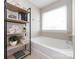 Bright bathroom showcases a soaking tub next to the window and stylish shelving unit at 15225 Kissimmee Ln, Mint Hill, NC 28227