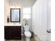 Well-lit bathroom featuring a dark wood vanity, white toilet, and shower with curtain at 15225 Kissimmee Ln, Mint Hill, NC 28227