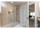 Bathroom with a glass door shower with built-in shelving, door to hall, and vanity just out of frame at 15225 Kissimmee Ln, Mint Hill, NC 28227