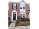 Inviting brick townhouse with a green front door, decorative wreath, and manicured shrubs at 19057 Coachmans Trce, Cornelius, NC 28031