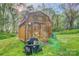A rustic wooden shed featuring double doors, a lawnmower in front, and lush greenery around it at 2006 Kollege Ln, Crouse, NC 28033