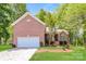 Inviting brick home featuring a two-car garage, a well-manicured lawn, and lush landscaping at 2104 Congress Ct, Kannapolis, NC 28083