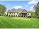 Expansive backyard view of a brick house with a covered back porch overlooking a well-manicured lawn at 4012 Flagstone Dr, Lancaster, SC 29720