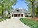 View of a brick home featuring a three-car garage and a curved driveway, surrounded by mature trees at 4012 Flagstone Dr, Lancaster, SC 29720