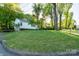 View of the home's exterior with verdant lawn and sun dappled trees at 676 Forest Nw St, Concord, NC 28025