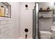 Bright bathroom featuring a tub with glass door, floating shelves, white subway tiles, and a toilet at 718 W Trade St # 808, Charlotte, NC 28202
