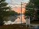 Peaceful lake view at dawn with a covered dock and lush greenery along the shore at 7268 Kiskadee Dr, Denver, NC 28037