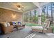 Relaxing screened-in porch with a brick wall, comfortable seating, and a view of the wooded surroundings at 7268 Kiskadee Dr, Denver, NC 28037