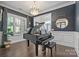 Elegant living room features a grand piano, chandelier lighting, and sophisticated decor, perfect for entertaining and relaxation at 7944 Park Rd, Charlotte, NC 28210