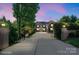 Elegant home with gated entrance, long driveway, and manicured landscaping visible at dusk at 7944 Park Rd, Charlotte, NC 28210