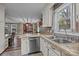Bright kitchen with white cabinets, stainless steel dishwasher and stone countertops at 813 Deer Path Pl, Mooresville, NC 28115