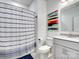 Fresh bathroom features a single sink vanity, toilet, and shower with a blue and white striped curtain at 9710 Ainslie Downs St, Charlotte, NC 28273