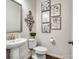 Stylish half-bathroom with modern fixtures, a pedestal sink, decorative art, and dark wood flooring at 9710 Ainslie Downs St, Charlotte, NC 28273