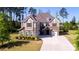 Inviting two-story home with stone and siding, featuring a lush green lawn, mature trees, and a wide driveway at 9878 Verdun Ct, Fort Mill, SC 29707