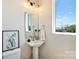 Stylish powder room with pedestal sink, framed art, and natural light from a window at 1105 Reece Rd, Charlotte, NC 28209