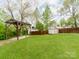 Spacious backyard features green grass, a wooden fence, storage shed, and covered patio at 1113 Gregory Ln, Statesville, NC 28677