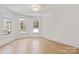 Bright, empty bedroom with hardwood floors, white trim, and arched windows with lots of natural light at 15603 Mccullers Ct, Charlotte, NC 28277