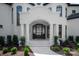 Home's entrance with stone steps, arched entryway, black door, white columns, and beautiful landscaping at 15603 Mccullers Ct, Charlotte, NC 28277