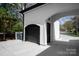 Side view of attached garage featuring black garage door, arched entrance, and additional entry door at 15603 Mccullers Ct, Charlotte, NC 28277