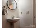 Modern powder room featuring a pedestal sink, round mirror, and neutral decor at 1814 Woods Ln, Denver, NC 28037