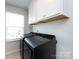 Well-lit laundry room with modern black washer and dryer, and bright white cabinetry at 2018 Sewall Sw Ave, Concord, NC 28025