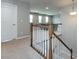View of the carpeted staircase with white wood railing leading to an open room with lots of natural light at 2018 Sewall Sw Ave, Concord, NC 28025