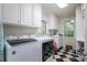 Bright laundry room with black and white tile floors, white cabinets, sink and washer and dryer at 2515 Sheffield Dr, Gastonia, NC 28054
