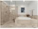 Luxurious bathroom featuring a separate glass shower, soaking tub, and stone tile at 2823 Providence Rd # 143, Charlotte, NC 28211