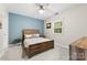 Well-lit bedroom with ceiling fan, window, side table, and a soothing blue accent wall at 3224 Selwyn Farms Ln # 3, Charlotte, NC 28209