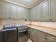 Well-lit laundry room equipped with modern washer, dryer, granite countertops, and ample cabinet storage at 4400 Sharon View Rd, Charlotte, NC 28226