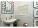 Charming powder room with pedestal sink, decorative mirror, and light gray walls at 5121 Alysheba Dr, Indian Trail, NC 28079