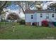 Backyard view of home featuring green lawn, shrubbery, and vinyl siding at 526 Arlington Ave, Albemarle, NC 28001