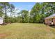 A spacious backyard with green grass, tall trees, and a brick house on a sunny day at 5762 Hightower Rd, Fort Lawn, SC 29714