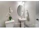 Chic powder room with pedestal sink, oval mirror, and minimalist decor at 7144 Hodges Meadow Ln, Charlotte, NC 28213