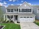 Charming two-story home with a well-manicured lawn, two-car garage, and inviting front porch with rocking chairs at 1018 Hinson Forest Rd, Monroe, NC 28110