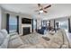 Cozy living room with a fireplace, ceiling fan, large windows, and an open view of the dining area at 1018 Hinson Forest Rd, Monroe, NC 28110