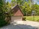 A red brick garage with tan door, complemented by a basketball hoop and bordered by mature trees at 1116 Landons Ct, China Grove, NC 28023
