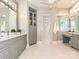 This bathroom features gray cabinets, dual sinks, a glass shower, marble tile, and a vanity area at 11447 Egrets Point Dr, Charlotte, NC 28278