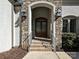 Elegant home entrance featuring brick steps, stone accents, and stylish lanterns creating a welcoming ambiance at 11447 Egrets Point Dr, Charlotte, NC 28278
