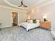 View of the primary bedroom featuring neutral walls, plush carpet, a tray ceiling with fan, and wood bedside tables at 11447 Egrets Point Dr, Charlotte, NC 28278