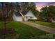 Exterior home elevation showcasing a landscaped front yard and asphalt driveway at sunset at 117 Heath Ln, Mooresville, NC 28117
