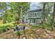 Spacious backyard featuring a patio area, a stone fire pit, and an enclosed sunroom, all surrounded by trees at 11700 Fernhurst Ln, Charlotte, NC 28277
